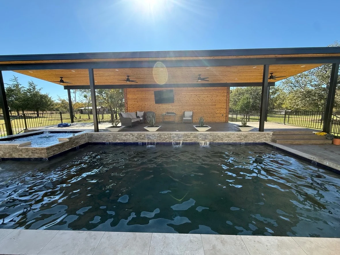 Completed Averra backyard with covered pavilion, water features, stonework, and poolside outdoor living